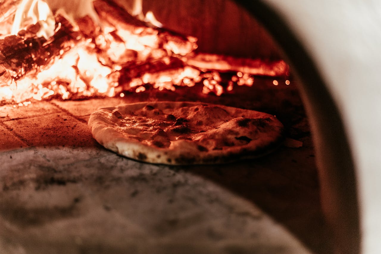 Close-up of a pizza baking in a traditional wood-fired oven.